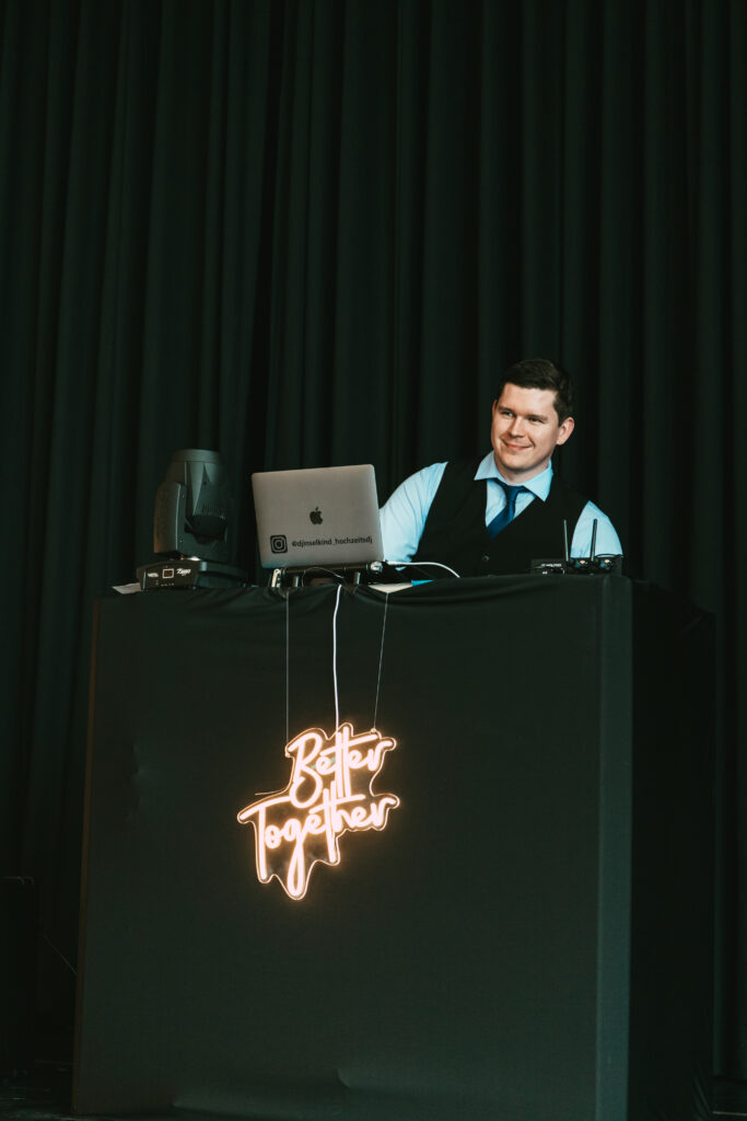 Ein DJ in Anzug, Insekind Cornell Walter, Hochzeitsexperte aus Kassel, hinter dem Mischpult auf einer eleganten Hochzeit in Göttingen.